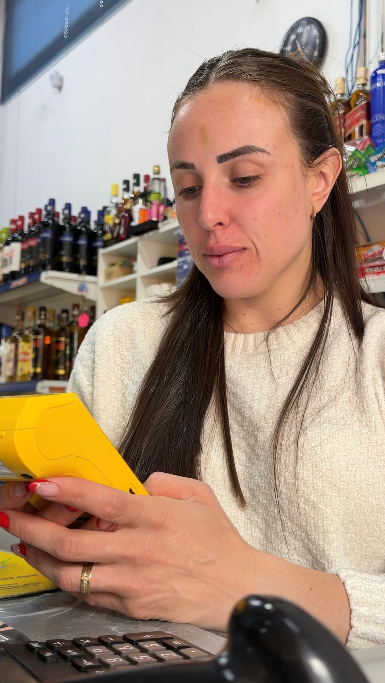 Aline trabalhando no mercado, segurando uma maquininha amarela