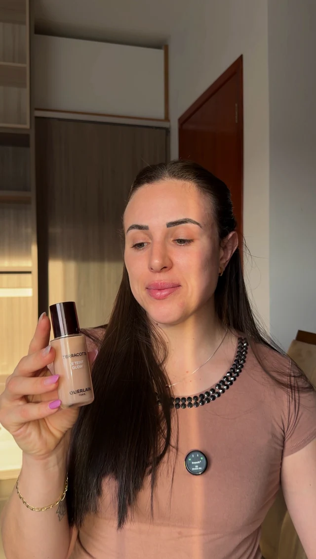 Aline observando uma base de maquiagem durante a apresentação do produto
